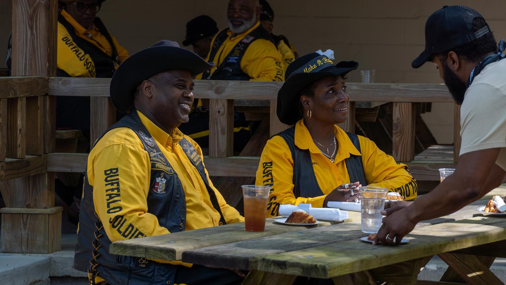 Three people sitting at a picnic table